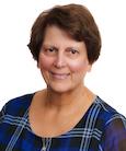 Headshot: Woman in dark top smiling at the camera